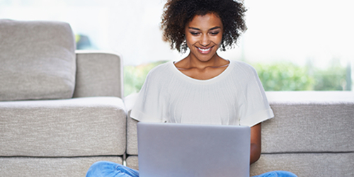 Photo of a woman sitting cross-legged while typing on a laptop, symbolizing blogging.