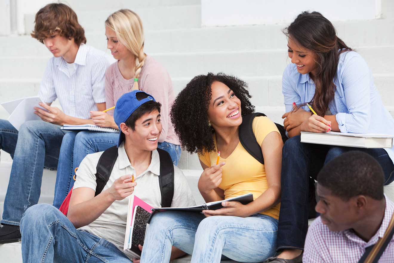 Students sitting together on steps laughing and talking together 