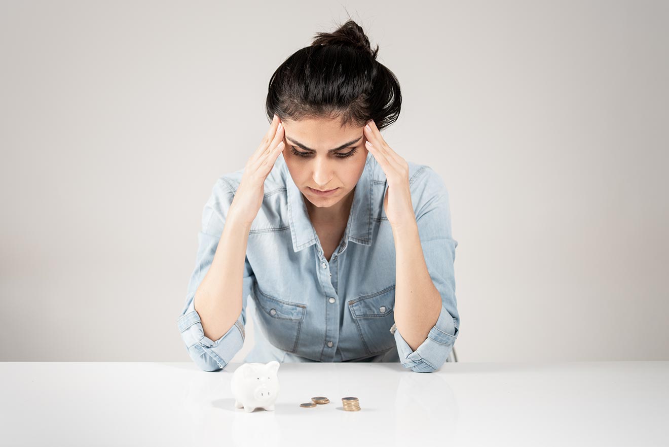 Woman looking at money on the table in front of her appearing stressed 