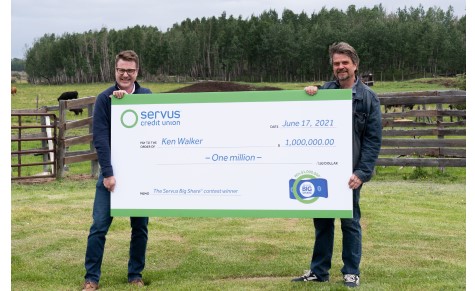 Photograph of the Big Share Contest's million dollar winner Ken Walker (right) holding an oversized cheque with Servus Credit Union CEO Ian Burns (left).