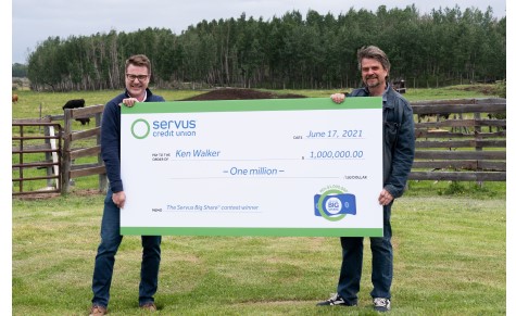 Photograph of the Big Share Contest's million dollar winner Ken Walker (right) holding an oversized cheque with Servus Credit Union CEO Ian Burns (left).