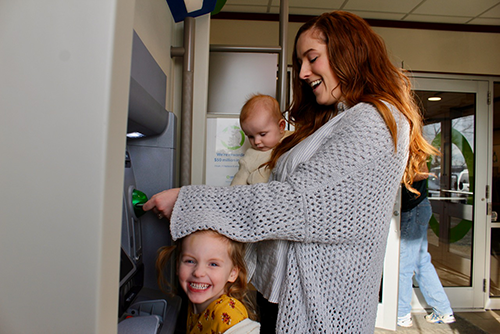 Hannah Kaup, with her daughters, using a Servus ATM.