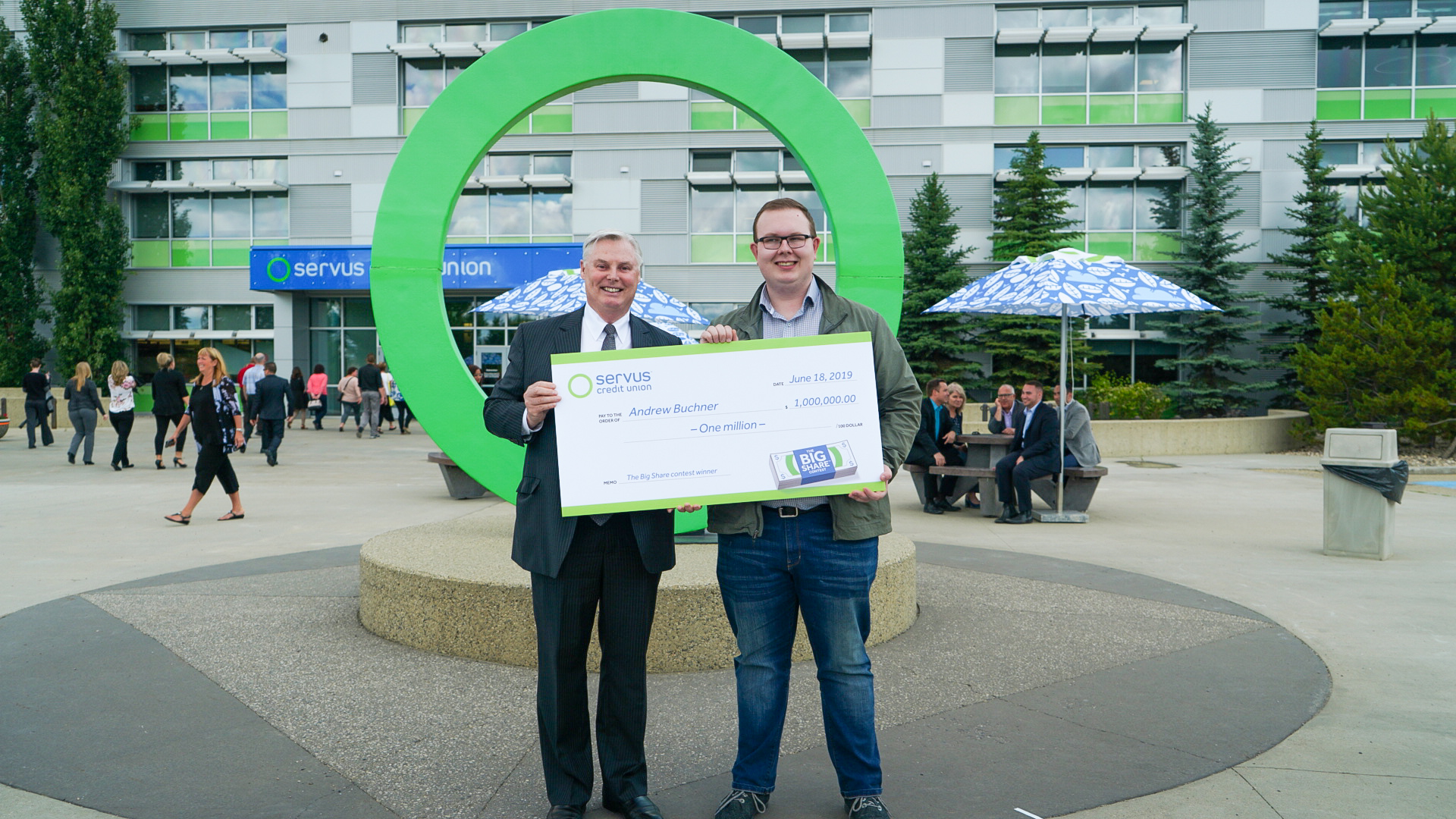 Photograph of the Big Share Contest's million dollar winner Andrew holding an oversized cheque with Servus Credit Union CEO Garth Warner.